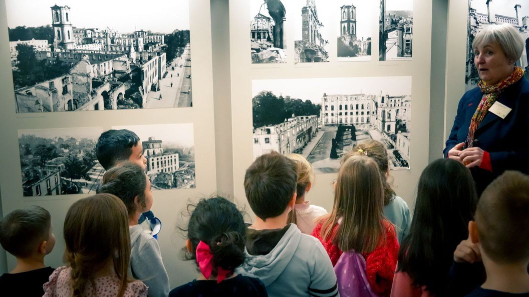 Schloss Bruchsal, innen, Schlossführerin mit Kindern vor Schwarz-Weiß-Fotografien von Schloss Bruchsal nach seiner Zerstörung im Zweiten Weltkrieg