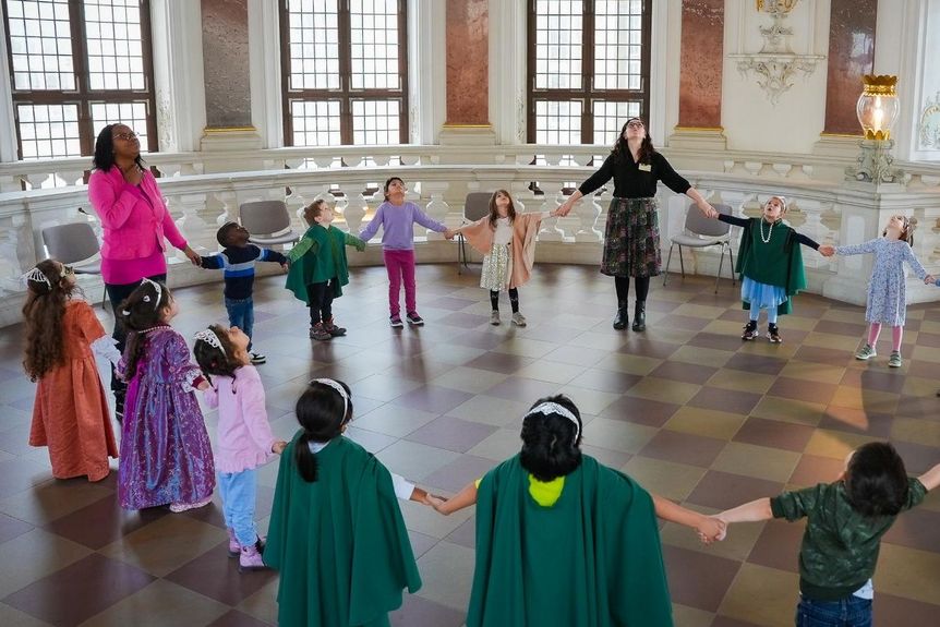 Schloss Bruchsal, Kuppelsaal, verkleidete Kinder und ihre Begleitpersonen bilden einen Kreis und blicken in die Kuppel