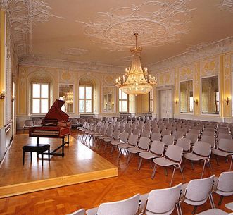 Salle de Musique de chambre avec piano à queue et rangées de sièges au château de Bruchsal 