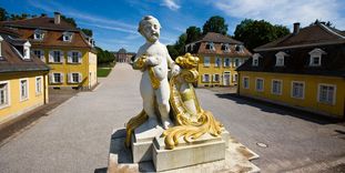 Putto am Eingang zur Gartenseite von Schloss Bruchsal mit dahinterliegenden Gebäuden, die einst als Wohnung für wichtige Hofangestellte dienten